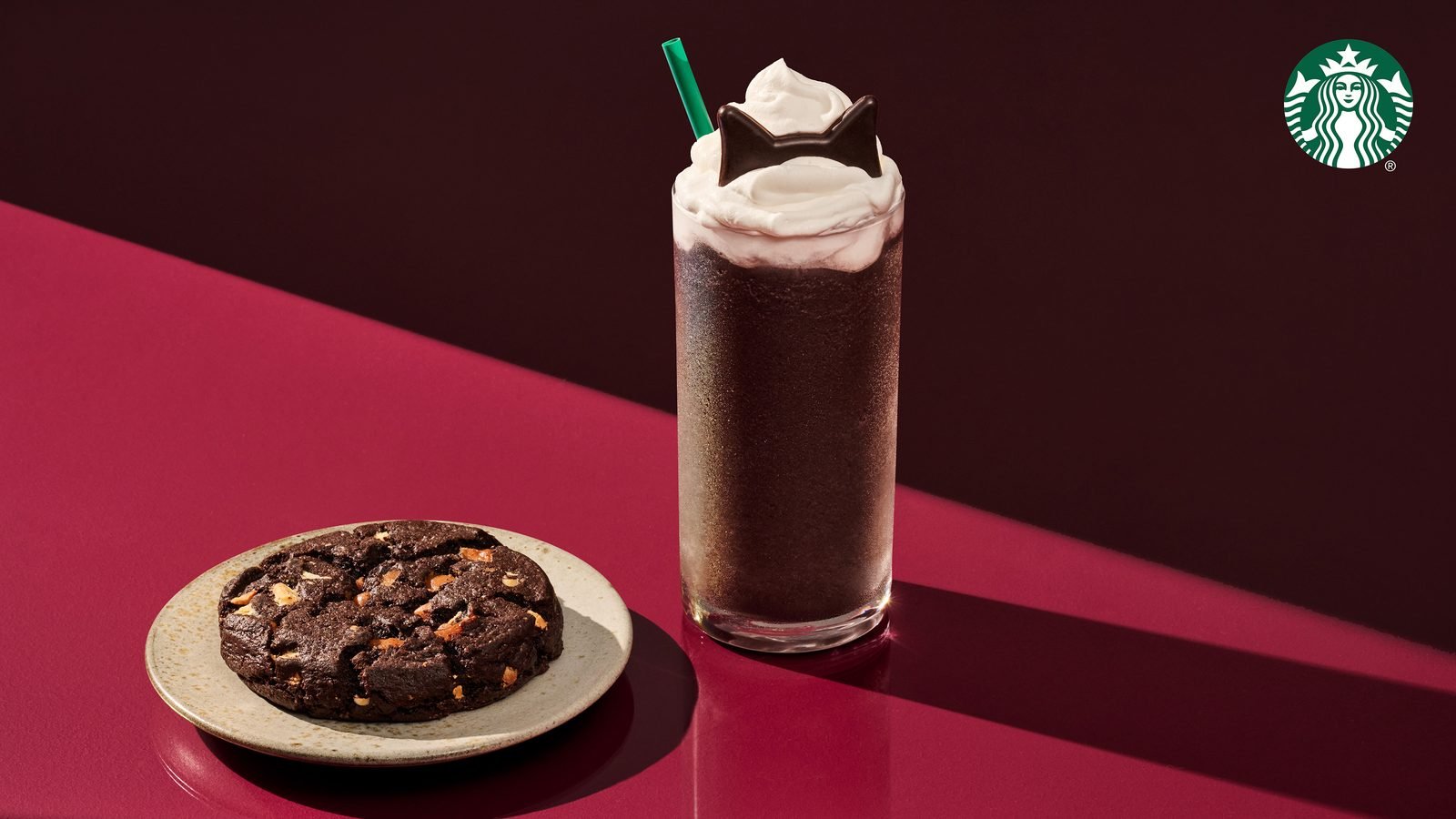Starbucks Black Cat Frappuccino with whipped cream and chocolate cat ears next to the Venti Black Night Cookie